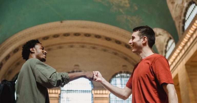 Respect - Cheerful young multiracial male friends bumping fists in old building