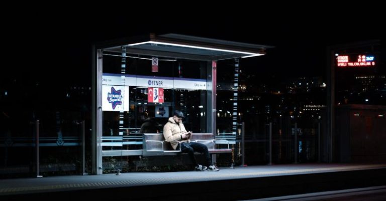 Stops - A man sitting at a bus stop at night