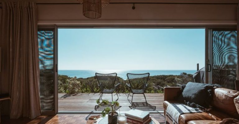 Accommodations - Interior design of luxurious apartment with large balcony doors and wooden terrace having picturesque view on green forested seashore and calm blue sea