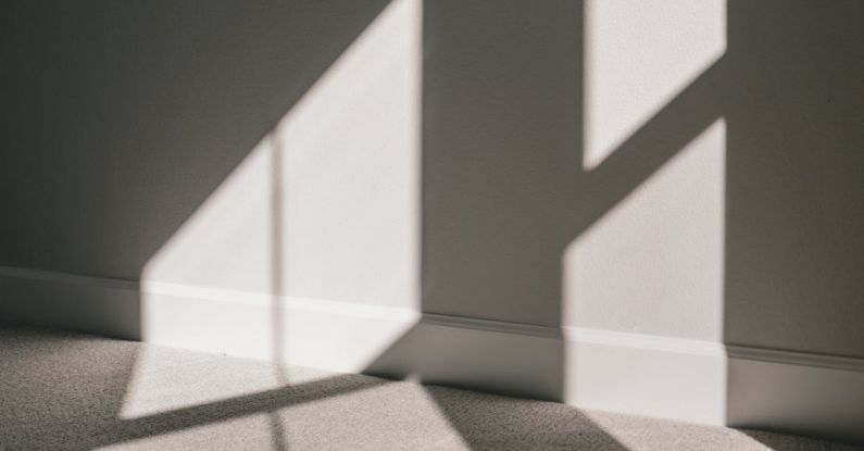 Accommodations - Shadow of window with glazing bars on wall and floor of minimal apartment in sunlight