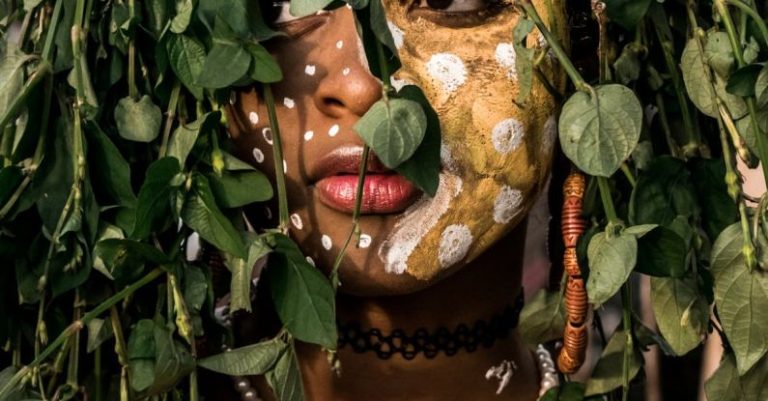 Indigenous Festivals - Person With Face Paint Behind Leaves Of A Plant